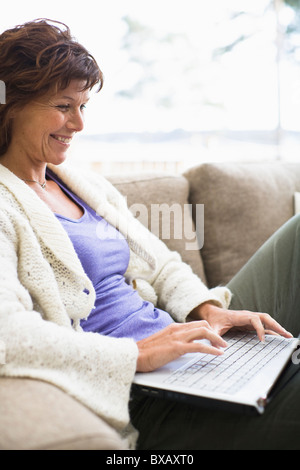 Femme assise sur un canapé et internet surf Banque D'Images