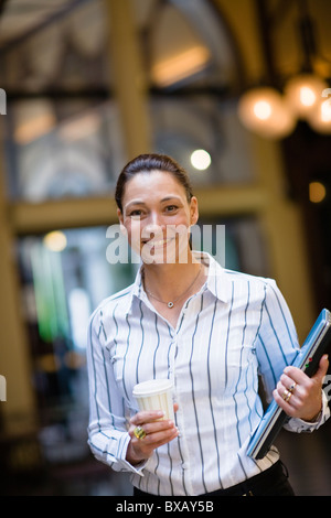 Portrait of businesswoman holding café à emporter dans une main et dans un autre ordinateur portable Banque D'Images
