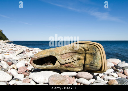 Ancienne chaussure endommagé sur stone beach Banque D'Images