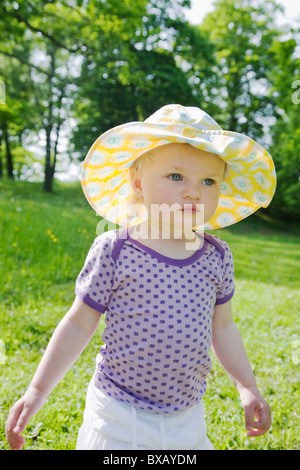 Girl wearing spotted sun hat standing in meadow Banque D'Images