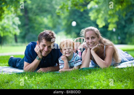 Les parents avec fils couché dans park et looking at camera Banque D'Images