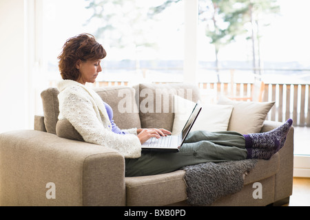 Femme assise sur un canapé et internet surf Banque D'Images