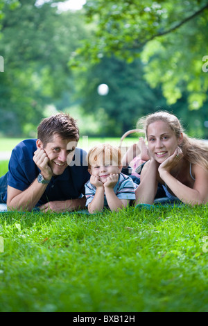 Les parents avec fils couché dans park et looking at camera Banque D'Images