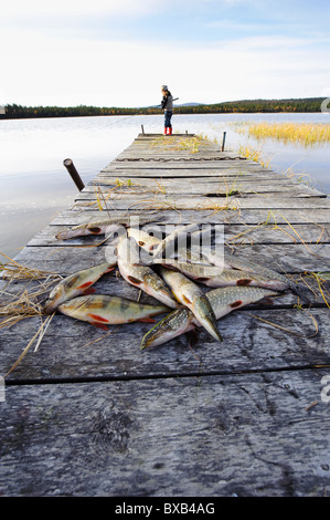 Poisson mort couché sur jetty, girl fishing dans l'arrière-plan Banque D'Images