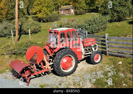 Le tracteur sur chemin de terre, maison en bois dans l'arrière-plan Banque D'Images