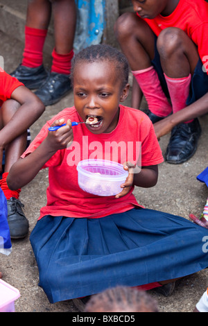 Fille de manger des aliments offerts à l'école dans la Maji Mazuri bidonvilles de Mathare, à Nairobi, Kenya Banque D'Images