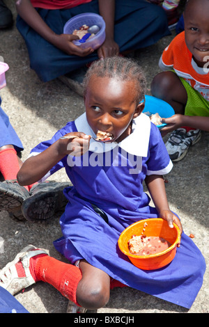 Fille de manger des aliments offerts à l'école dans la Maji Mazuri bidonvilles de Mathare, à Nairobi, Kenya Banque D'Images