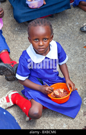 Fille de manger des aliments offerts à l'école dans la Maji Mazuri bidonvilles de Mathare, à Nairobi, Kenya Banque D'Images