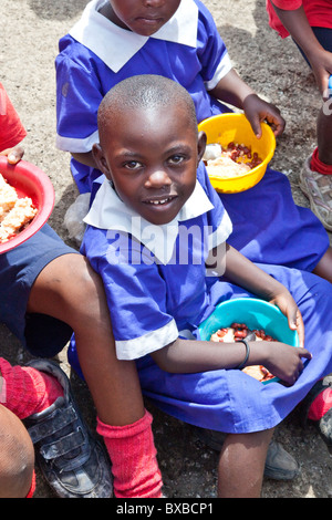 Fille de manger des aliments offerts à l'école dans la Maji Mazuri bidonvilles de Mathare, à Nairobi, Kenya Banque D'Images