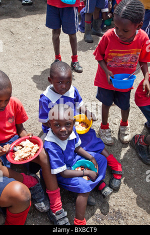 Les enfants de manger des aliments offerts à l'école dans la Maji Mazuri bidonvilles de Mathare, à Nairobi, Kenya Banque D'Images