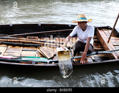Homme verser de l'eau de son bateau, Bangkok, Thailande, Asie Banque D'Images