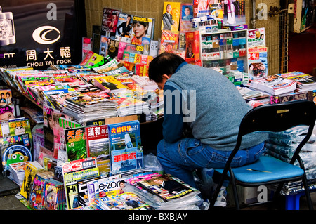 Asian man sitting at kiosque sur city street dans le centre-ville de Hong Kong, Chine Banque D'Images