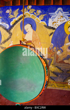 Tambour de prière en face d'une peinture murale bouddhiste au monastère de Thiksey au Ladakh Banque D'Images