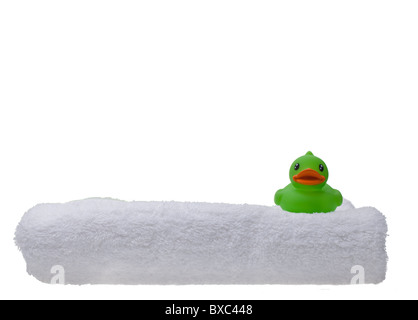 Canard en caoutchouc vert sur une serviette blanche pelucheuse isolés contre un arrière-plan transparent blanc Banque D'Images