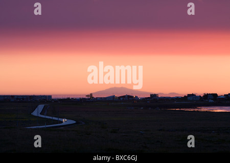 Voiture roulant au coucher du Soleil, soleil de minuit, l'Alftanes, sud-ouest de l'Islande. Glacier Snaefellsjokull en arrière-plan. Banque D'Images