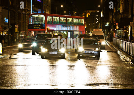 Les voitures et bus à impériale rouge en attente sur la rue à un feu rouge la nuit à Londres près de Piccadilly Circus Banque D'Images