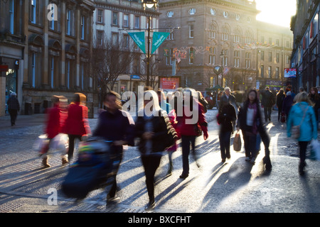 La silhouette urbaine Shoppers Noël dans les rues animées de Dundee, centre-ville, Tayside, Ecosse, Royaume-Uni. Silhouettes de personnes contre le faible soleil d'hiver. Banque D'Images