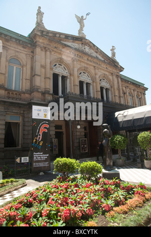 Jardin de fleurs en face du bâtiment avec portique, fenêtres, décorées fronton et trois statues sur le toit Banque D'Images