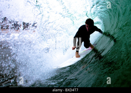 Un surfeur mâle rides le tube. Banque D'Images