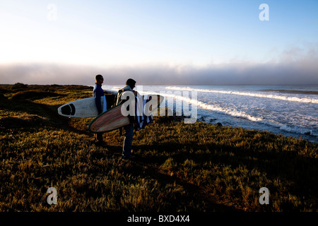 Deux jeunes surfeurs mâles randonnée pédestre le long d'un sentier. Banque D'Images