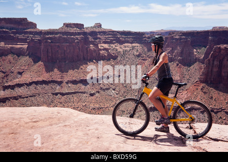 Une femme blanche bikes la piste de Rim en Utah. Banque D'Images