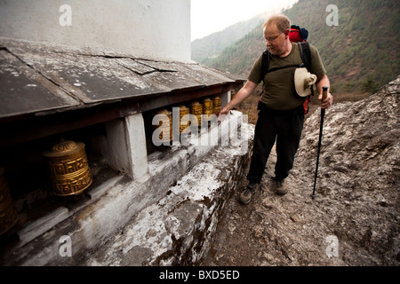 Un homme trekker tourne roues de prière lorsque vous suivez la piste de Lukla, au Népal. Banque D'Images