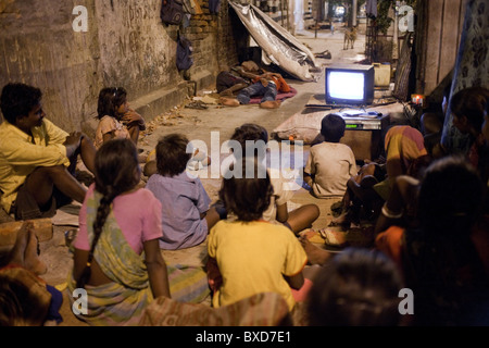 Un groupe de personnes sans domicile regarder la télévision pendant la nuit sur un trottoir à Kolkata, Inde. Banque D'Images