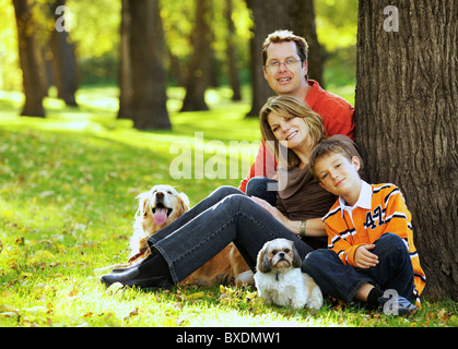 Heureux jeune famille posant devant l'appareil photo avec Golden Retriever et chiens Shih Tzu Banque D'Images