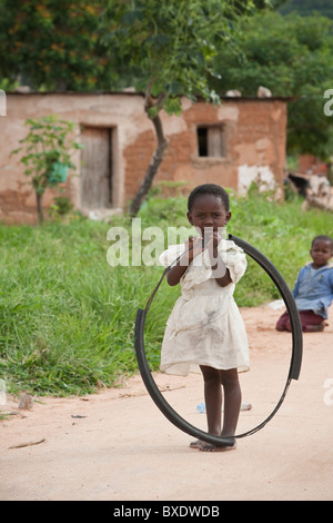 Un enfant se tient avec un pneu de vélo busted à Dodoma, Tanzanie, Afrique de l'Est. Banque D'Images