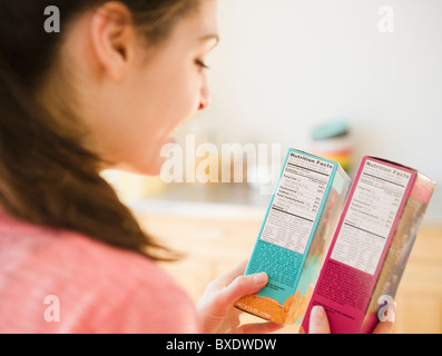 Femme lisant le tableau de la valeur nutritive sur les emballages alimentaires Banque D'Images