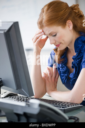 Frustrated businesswoman sitting at her desk Banque D'Images