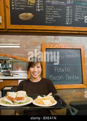 Woman holding tray of food in bakery Banque D'Images