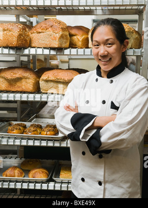 Chef debout à côté des plateaux de pâtisseries fraîchement Banque D'Images