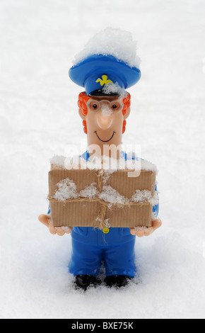 POSTMAN FIGURE AVEC COLIS DANS DES CONDITIONS MÉTÉOROLOGIQUES GLACIALES ENNEIGÉS DU BUREAU DE POSTE DE NOUVEAU DES RETARDS DE LIVRAISONS HIVER ETC UK POSTAL SERVICE Banque D'Images