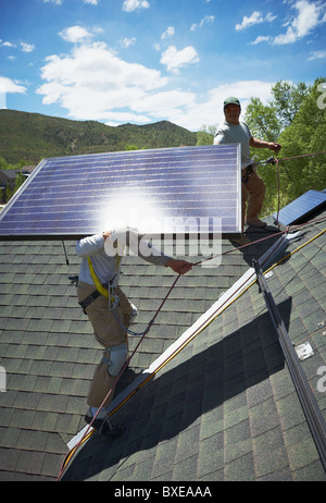 Les travailleurs de la construction l'installation de panneaux solaires sur le toit Banque D'Images