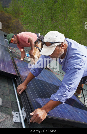 Les travailleurs de la construction l'installation de panneaux solaires sur le toit Banque D'Images