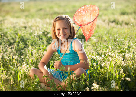 Jeune fille assise sur le terrain avec un filet à papillons Banque D'Images