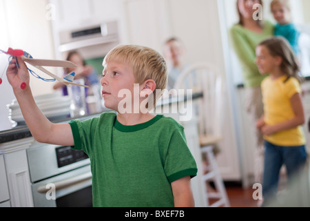 Young boy playing with toy airplane in kitchen Banque D'Images