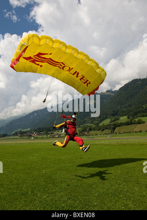 Parachutiste sous voile est d'atterrissage dans des nuages et se précipite sur les champs verts. Banque D'Images