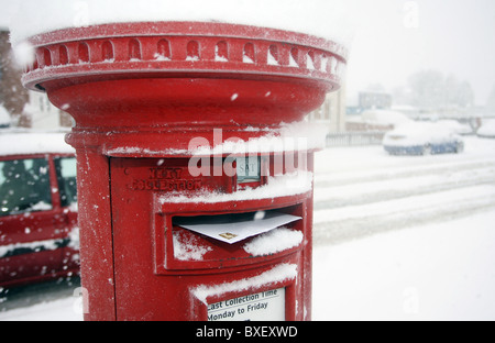 Un poste britannique fort rouge débordant de mail couvertes de neige Banque D'Images