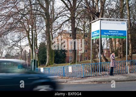 Une femme se tient en dehors de Nottingham City Hospital fumer une cigarette Banque D'Images