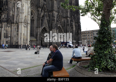 Des gens assis sur un banc en face de la cathédrale de Cologne Banque D'Images