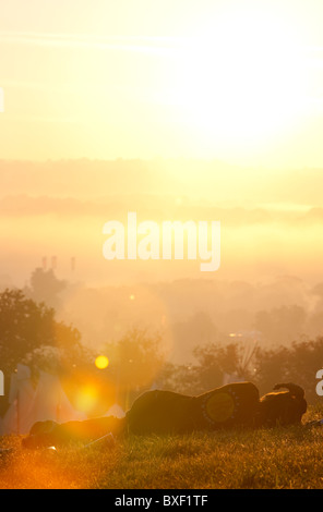 Homme passa sur l'herbe avec vue sur Glastonbury Festival au lever du soleil. Banque D'Images