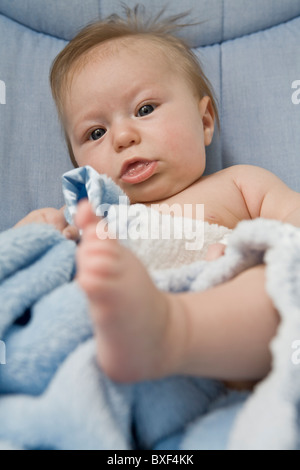 3 mois bébé garçon regardant son pied Banque D'Images