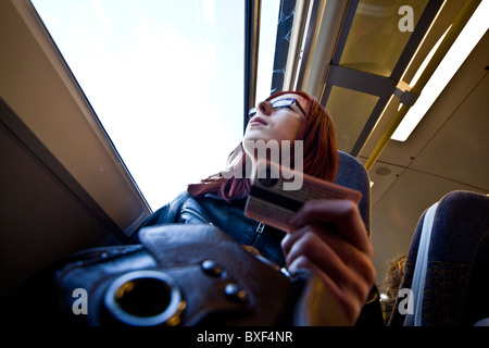 Jeune femme était assise sur un détenteur de billet de train, regarder par la fenêtre Banque D'Images