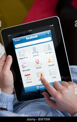 Femme à l'aide de site de réseautage social Facebook sur un iPad tablet computer Banque D'Images