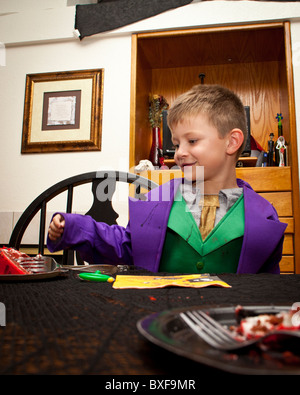 Un jeune garçon manger un gâteau et de boire du lait dans son costume Halloween Banque D'Images