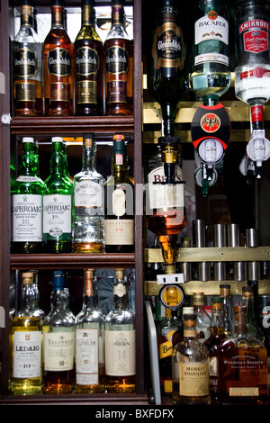 Une rangée de bouteilles affichant beaucoup de différentes marques de whiskies écossais derrière le bar à l'intérieur d'un pub local à Dundee, Royaume-Uni Banque D'Images