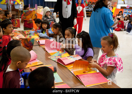 Les élèves regarder à travers leurs copies d'auteur Carmen Tafolla's English-french livre, 'Que peut-on faire avec une Paleta' à l'école Banque D'Images