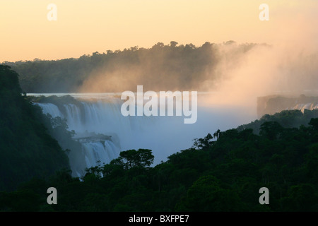 [Iguassu Falls] [Chutes] à l'aube avec début de la lumière du soleil en tournant le brouillard de pulvérisation, rouge à partir de l'hôtel Sheraton, côté Argentin
